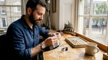 Jeweler polishing solitaire diamond ring at workbench